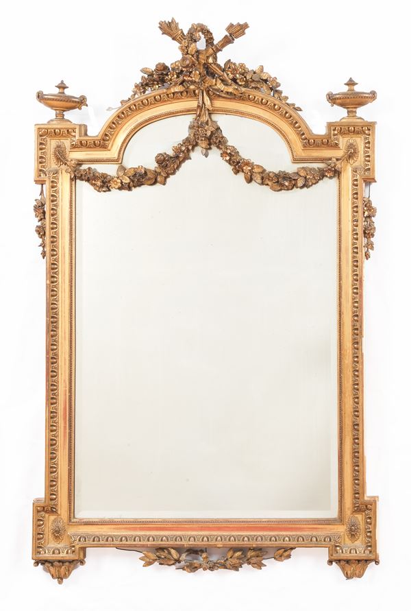 Antique French Louis XVI mirror in gilded wood, with a carved top with torch motifs, laurel wreath and floral interlacing. The mirror is not original, but is a ground mirror from the 60s. Slight missing parts and defects in the friezes