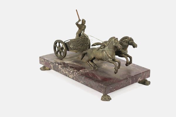 "Biga romana con auriga", scultura in bronzo con base in marmo brecciato, sorretta da quattro piedini ricurvi. La figura dell'auriga presenta difetti