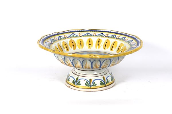 Fruttiera ad alzata in maiolica italiana policroma, con decorazioni floreali e geometriche, bordure in giallo. Lievi difetti