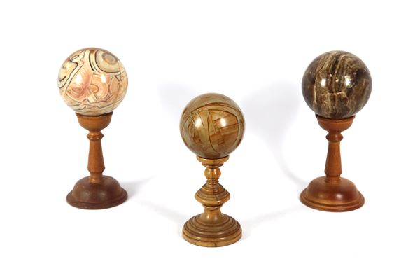 Lot of three spheres in various fine marbles, supported by turned column bases in walnut wood