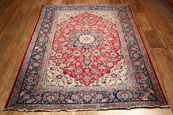 Persian rug Mashad with geometric floral design on red and brown background. The rug has a cut on one of the side edges