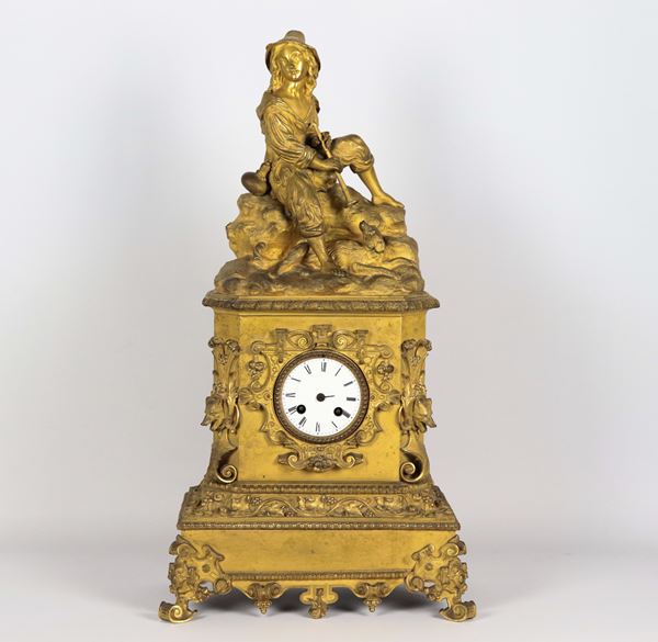 Antique Neapolitan table clock in gilded bronze, embossed and chiseled, with sculpture of a piper with a dog, white enamel dial with Roman numerals, missing hands. Not working, to be overhauled 