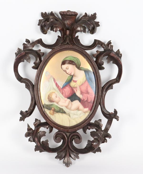 "Madonna con Bambino", placca ovale in porcellana variopinta in cornice in legno intagliato