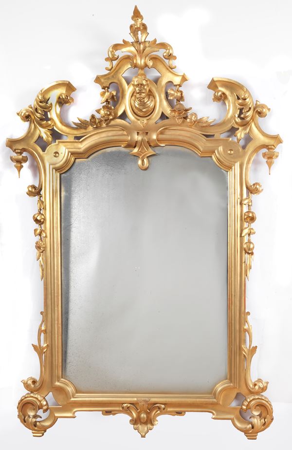 Antique mirror in gilded wood and carved with Louis XV motifs of acanthus leaves, curls and flowers, in the centre of the top a small bust of a man