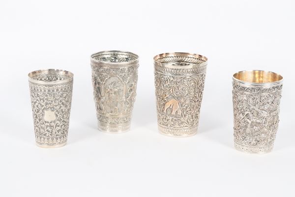 Lot of four oriental silver glasses, one of which in 925 silver, entirely chiselled and embossed with floral scroll motifs, deities and elephants, 590 g.