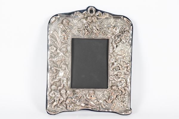 English silver picture frame, George V period, entirely chased and embossed with motifs of cherubs celebrating, the rear support is damaged