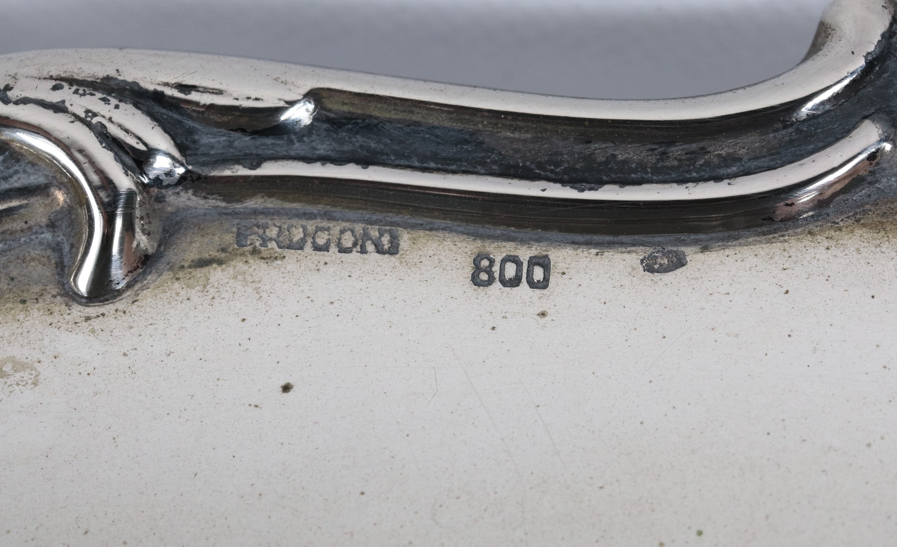 Centrotavola tondo in argento con bordo centinato, cesellato e sbalzato a motivi di volute e conc...