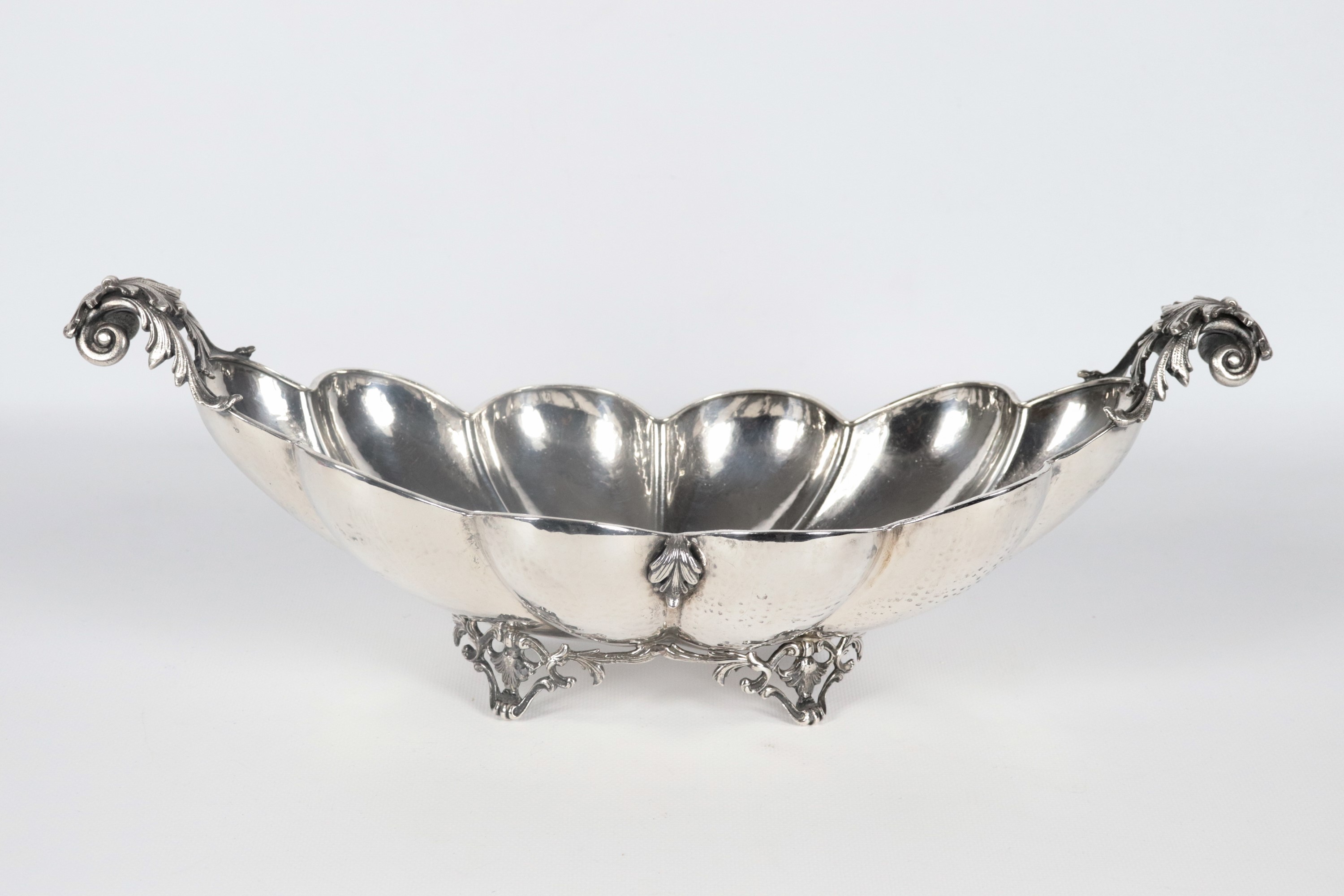 Centrotavola a barchetta in argento cesellato e sbalzato, con bordo centinato e sorretto da quatt...