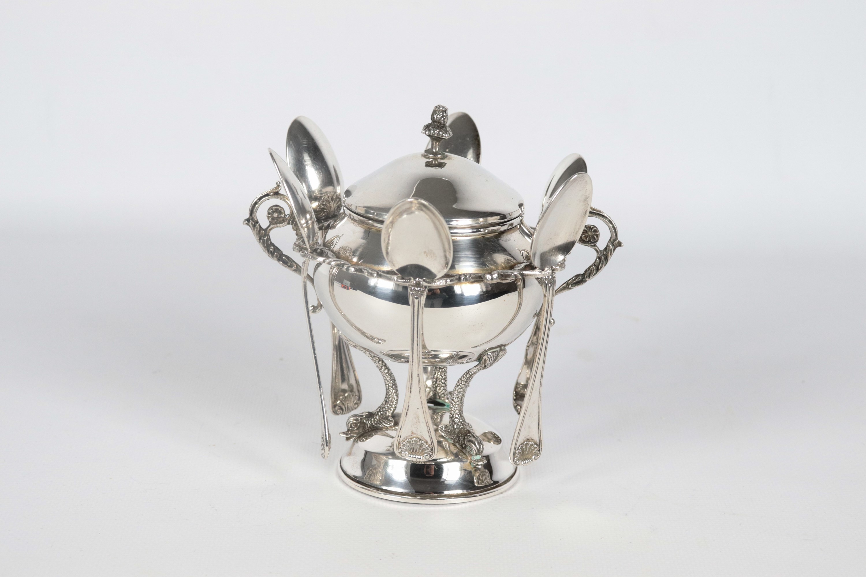 Zuccheriera in argento a forma di anfora con sei cucchiaini, sorretta da tre piccole sculture di ...