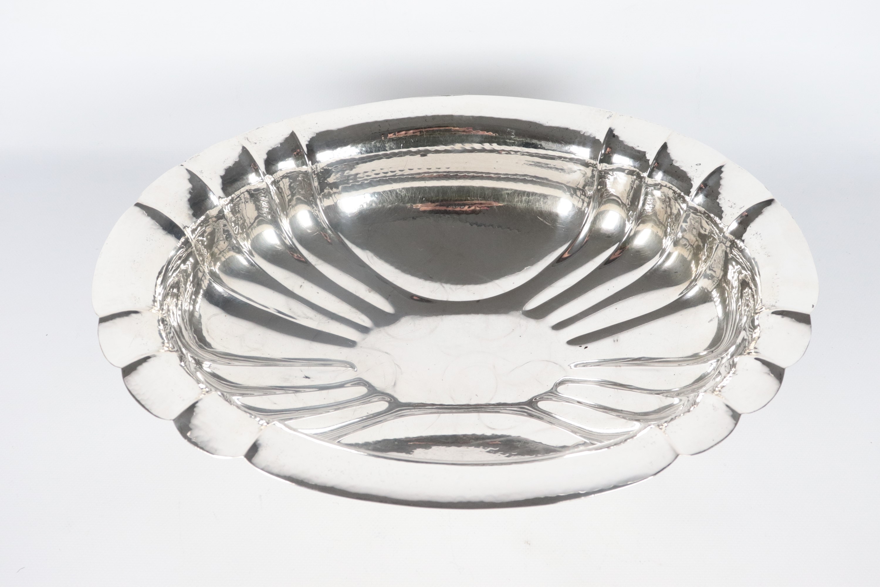 Centrotavola ovale in argento cesellato e sbalzato, con bordo centinato e sorretto da quattro pie...