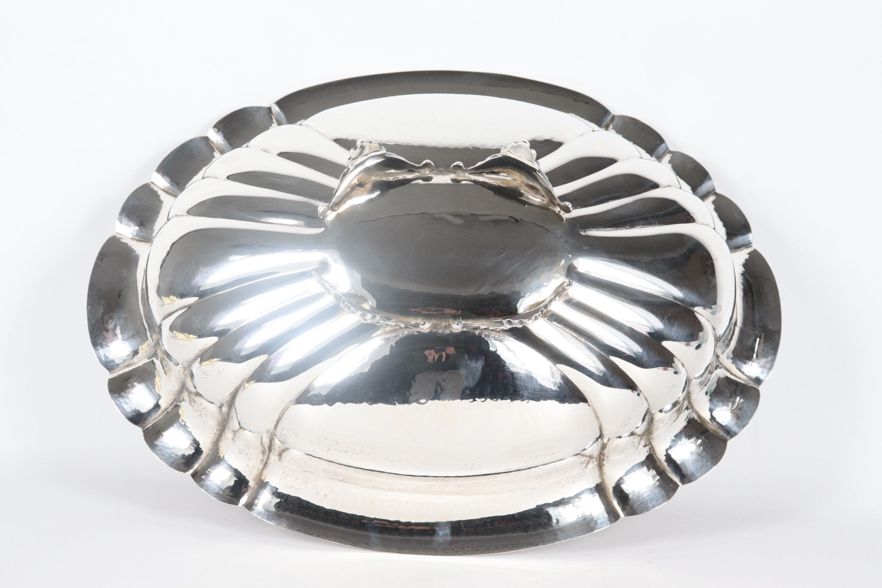 Centrotavola ovale in argento cesellato e sbalzato, con bordo centinato e sorretto da quattro pie...