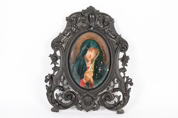 "Madonnina", antico piccolo dipinto ad olio su carta in cornice in legno ebanizzato, riccamente intagliata a motivi di volute, fiori e puttini. Varie cadute di colore. Secolo XIX
