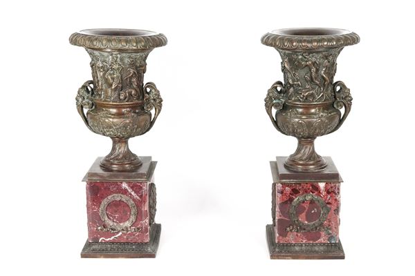Coppia di antiche anfore medicee francesi Epoca Napoleone III, in bronzo cesellato e sbalzato a motivi di scene mitologiche, manici a forma di teste di caproni e basi in marmo rosso di Francia con corone d'alloro 