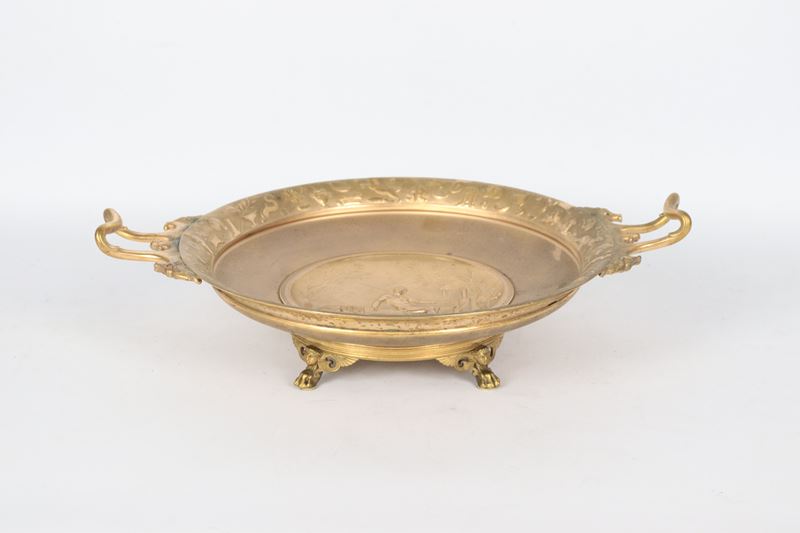 Firmata. "Aetas aurea", alzata in bronzo dorato e cesellato con medaglione centrale lavorato ad a...