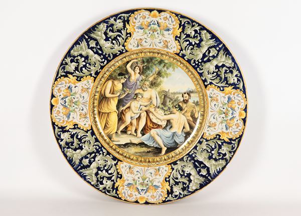 Large Neapolitan majolica display plate, entirely decorated and painted with floral scrolls and caryatids, with &quot;Baccanale&quot; in the centre