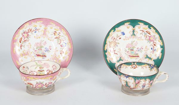 Coppia di antiche tazze con piattini in porcellana, interamente decorate e variopinte a motivi di ghirlande e mazzetti di fiori, una a fondo rosa antico e una a fondo verde. Fine XIX Secolo