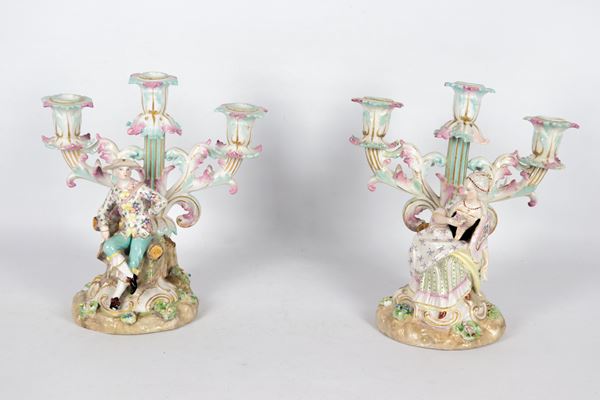 Coppia di antichi candelabri in porcellana di Sassonia, interamente decorati e variopinti con fiori e figure di "Dama" e "Cavaliere", 3 fiamme ciascuno. XIX Secolo