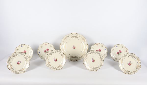 Fruit plate service in German porcelain from Bavaria, with colourful decorations featuring bouquets of flowers and golden garlands, consisting of a fruit bowl and eight saucers (9 pcs.). Manufacture from the early 20th century