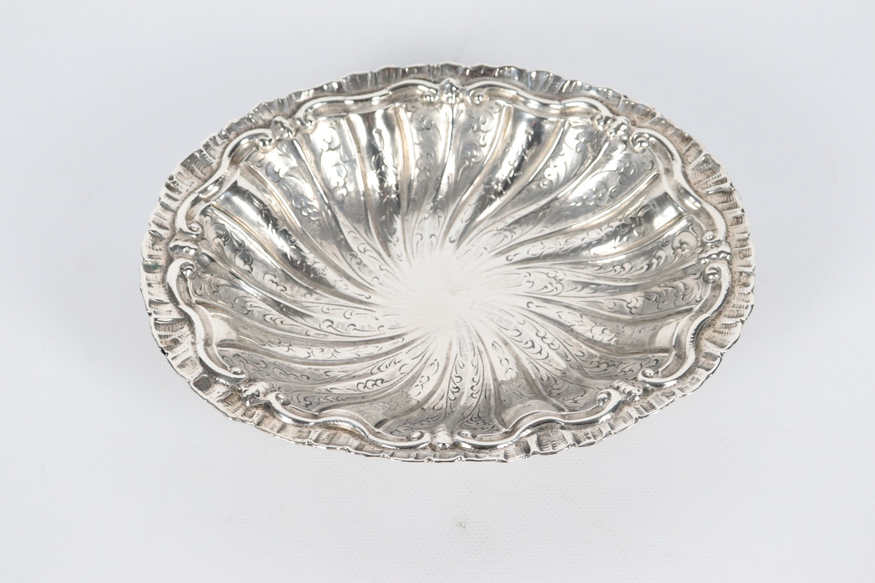 Antico piccolo centrotavola in argento a forma ovale, interamente cesellato e sbalzato a volute v...