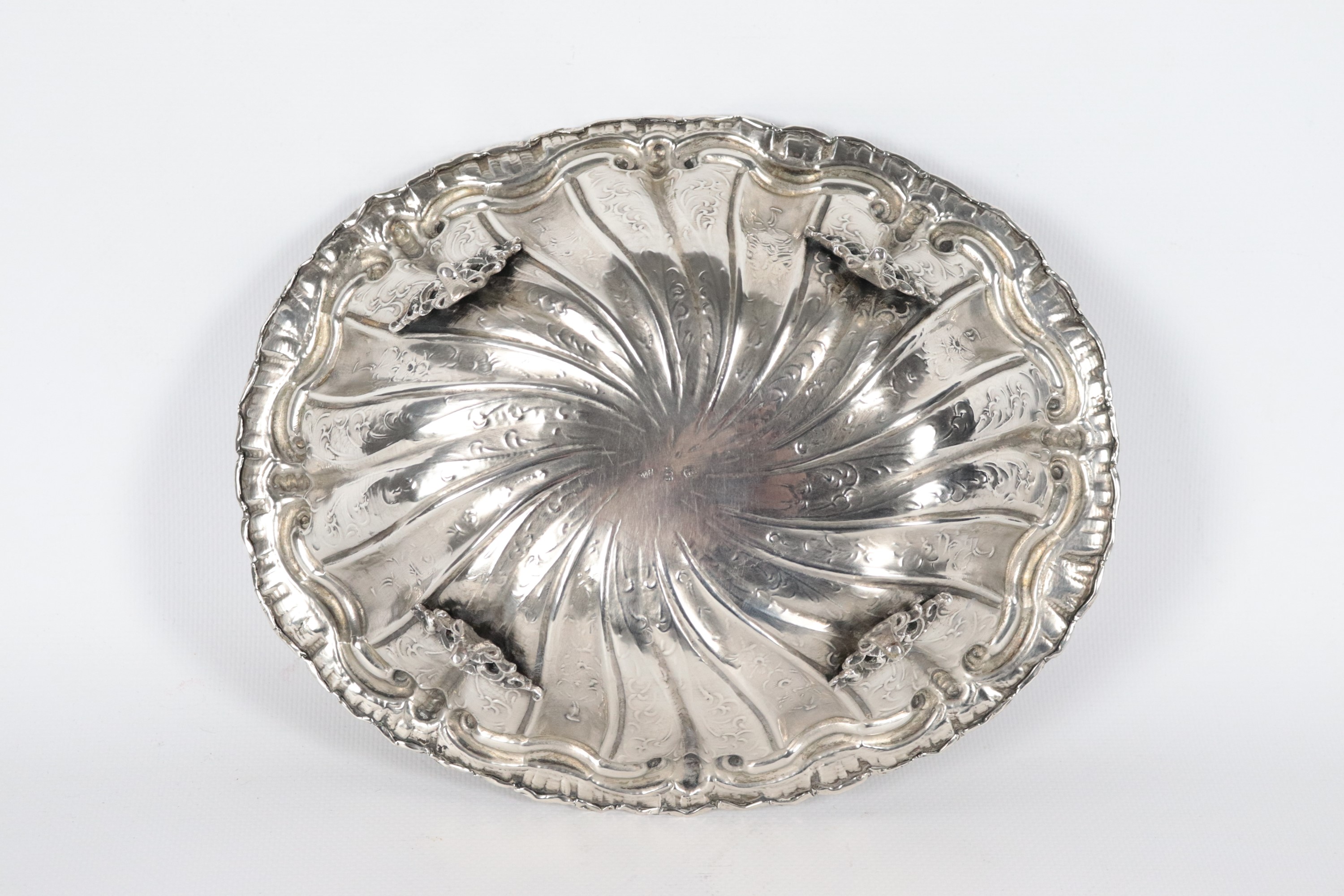 Antico piccolo centrotavola in argento a forma ovale, interamente cesellato e sbalzato a volute v...
