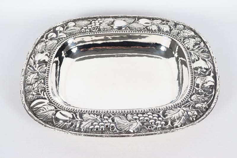 Grande fruttiera rettangolare in argento con bordo interamente cesellato e sbalzato a motivi di f...