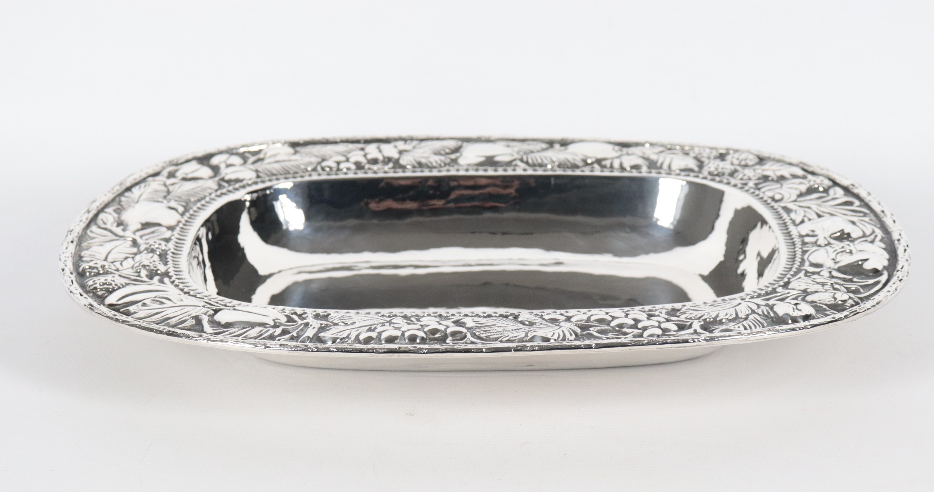 Grande fruttiera rettangolare in argento con bordo interamente cesellato e sbalzato a motivi di f...