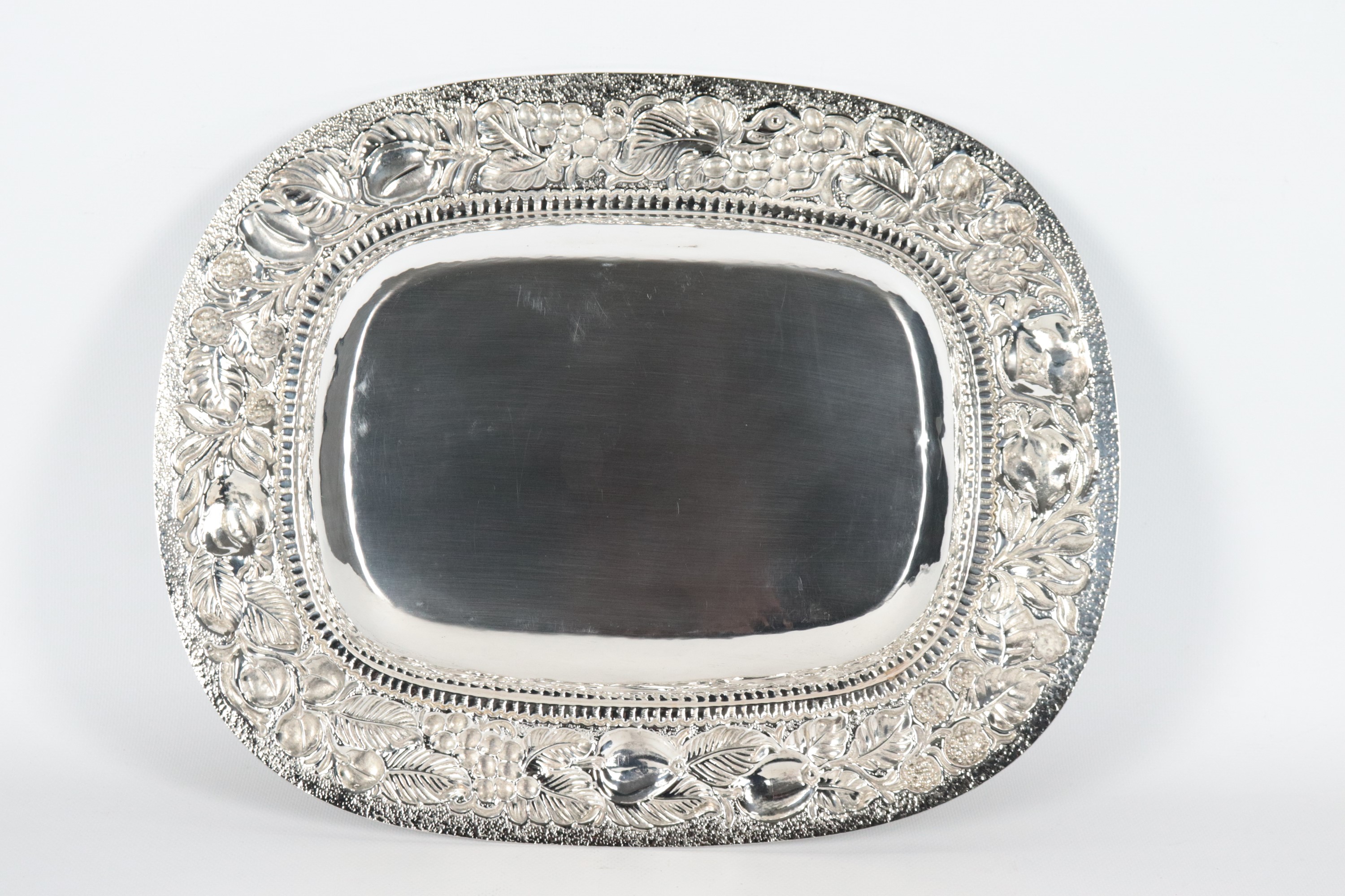 Grande fruttiera rettangolare in argento con bordo interamente cesellato e sbalzato a motivi di f...