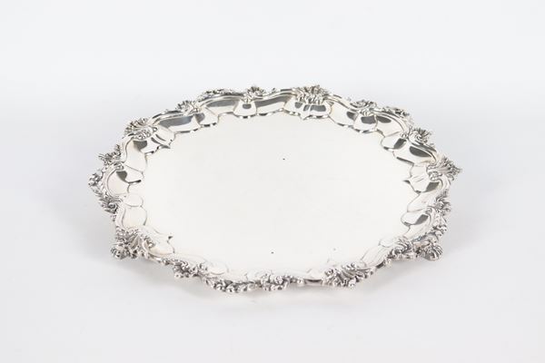 Antique English silver salver, George IV era, with a shaped and chased edge with scroll and shell motifs, supported by three lion feet. London 1826 hallmarks, 700 gr.