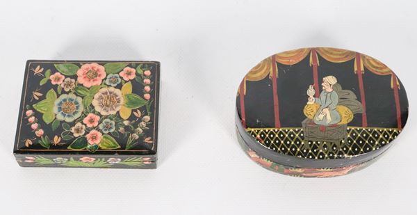 Lot of two Indian boxes in black lacquered wood, with relief decorations of a character and oriental flowers, one rectangular and one oval