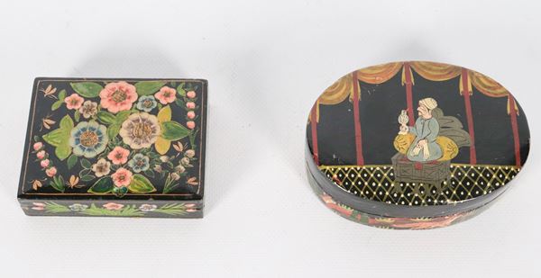 Lotto di due scatole indiane in legno laccato nero, con decorazioni a rilievo di personaggio e fiori orientali, una rettangolare e una ovale