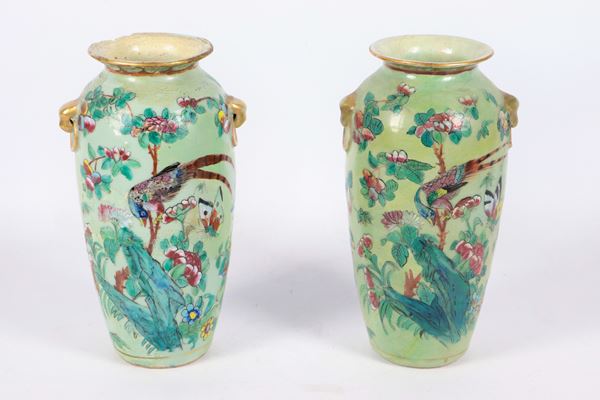 Pair of small antique Chinese porcelain vases, entirely decorated with polychrome enamels in relief with motifs of exotic birds, butterflies and flowers. The vases have restorations and breakages