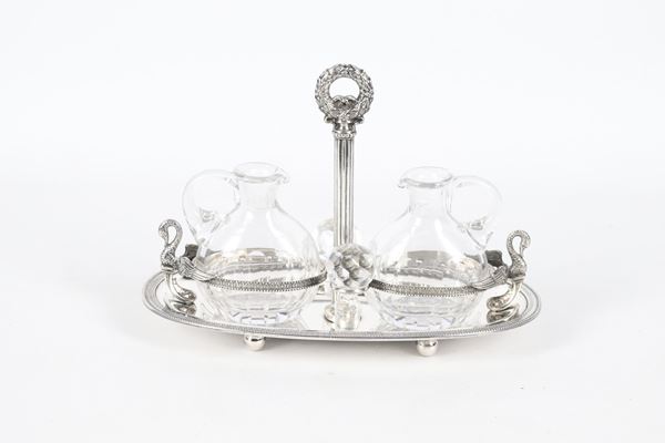 Antica oliera in argento cesellato e sbalzato a motivi neoclassici con cigni, palmette e corona d'alloro, due ampolle in cristallo, gr. 330
