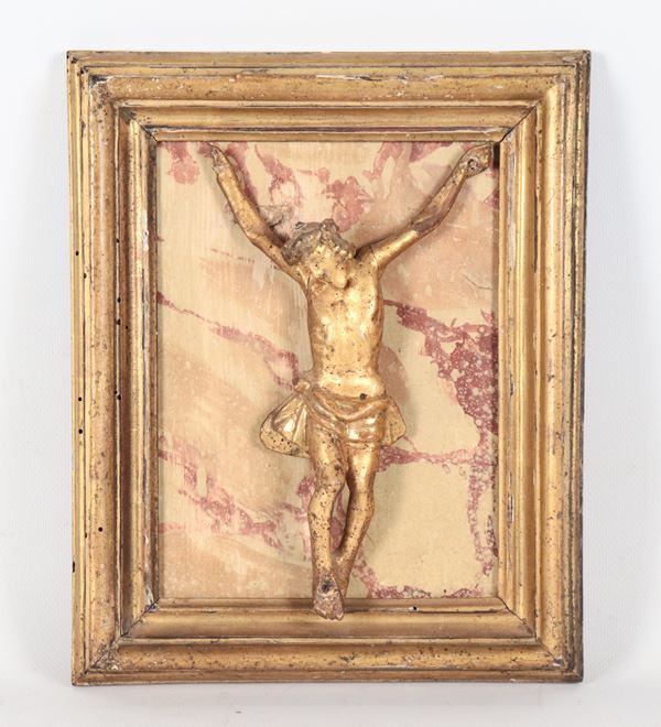 Antico piccolo Cristo in legno dorato e intagliato, in antica cornice dorata con fondo decorato a finto marmo
