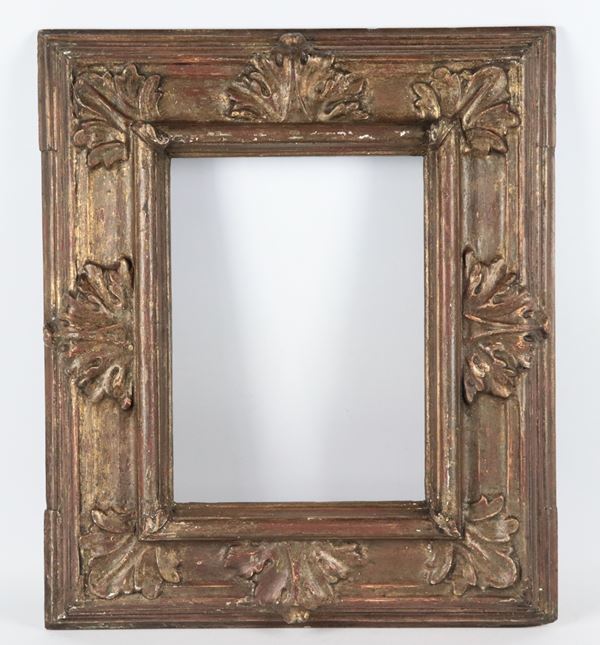 Antique patinated wooden frame with traces of gilding and carvings with palmette motifs